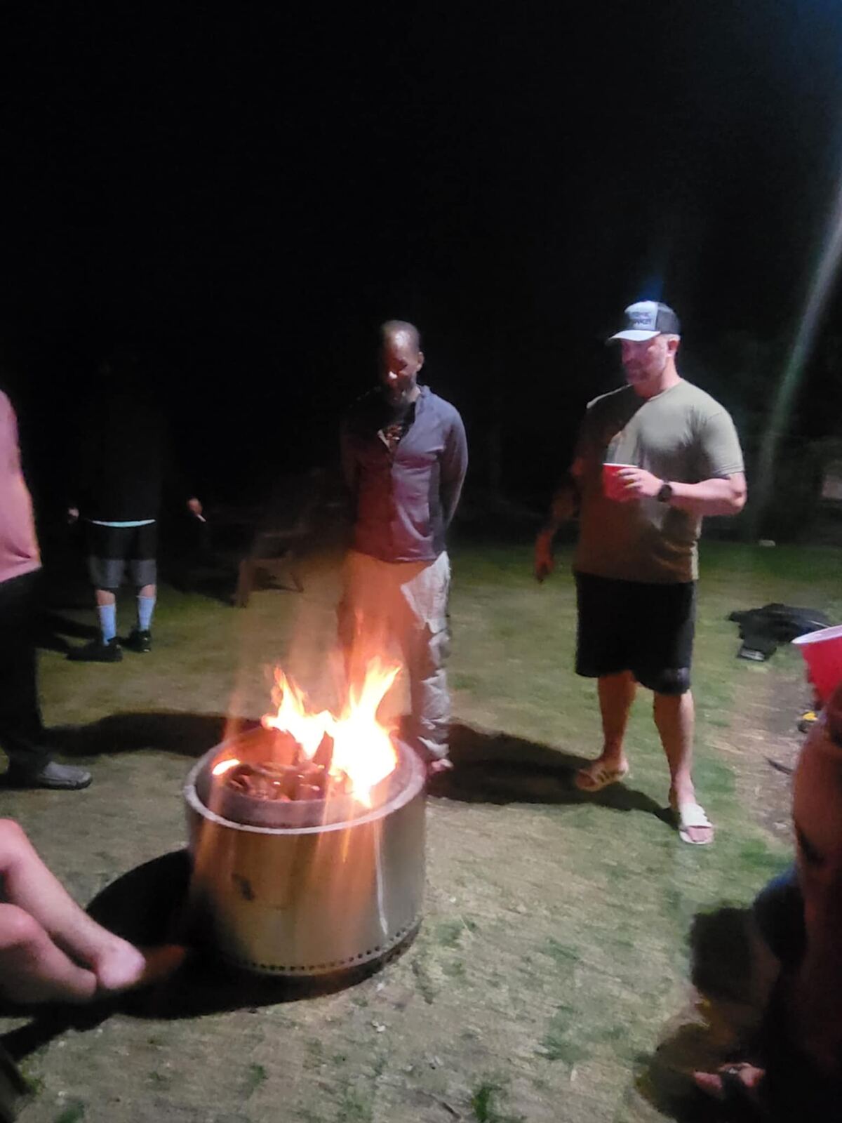 Late-night fire pit conversation — two brothers standing in the glow