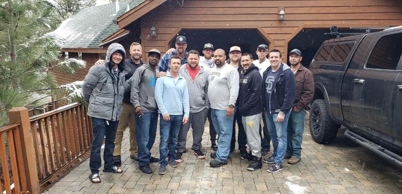 Snow-dusted cabin driveway crew shot in front of the lifted Ram