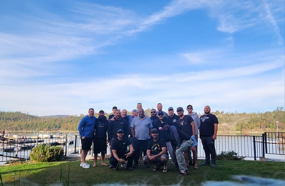 Bass Lake marina group photo — bluebird sky, full crew on the lawn