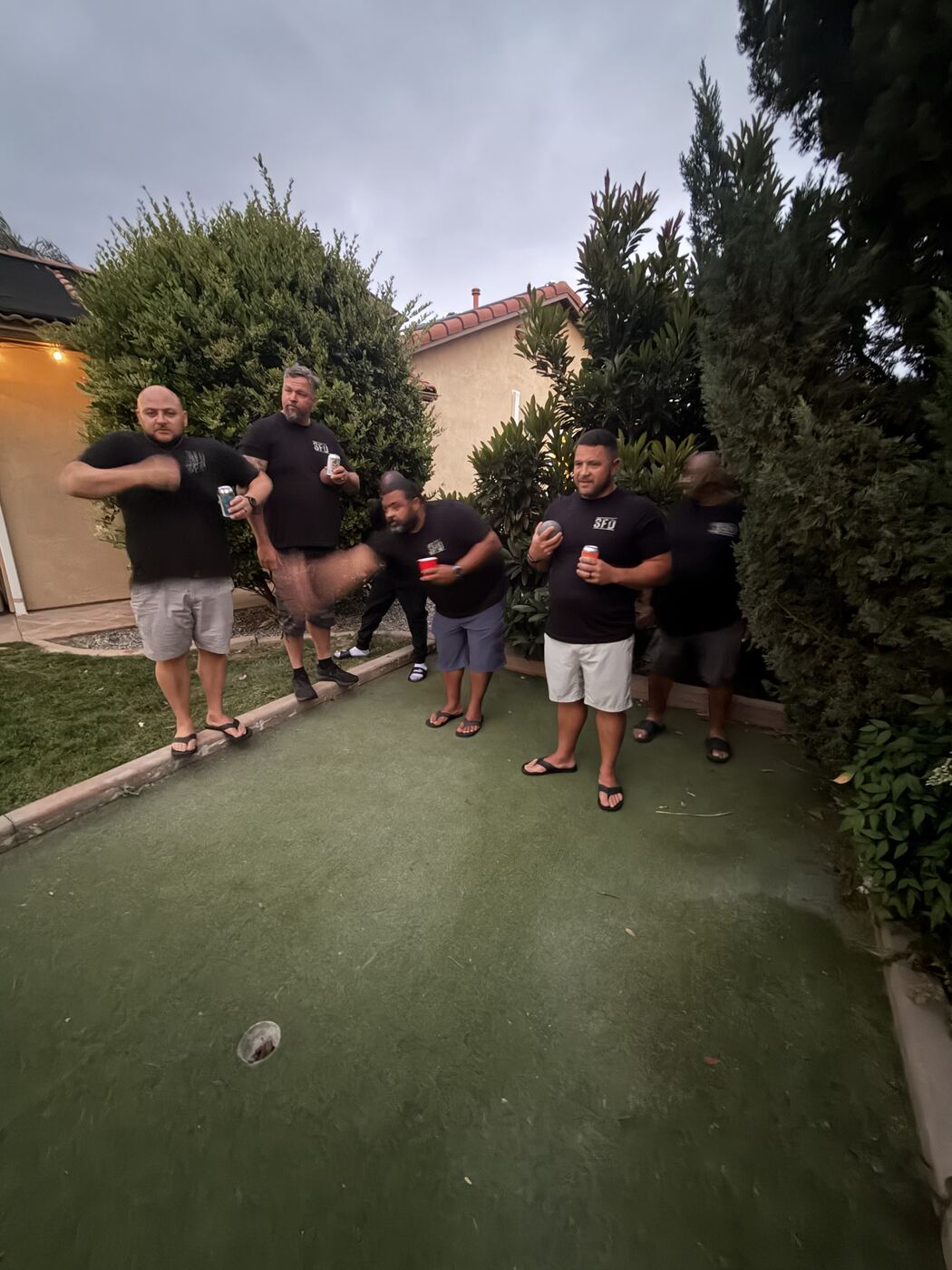 Backyard bocce ball at dusk — mid-throw, motion blur and all