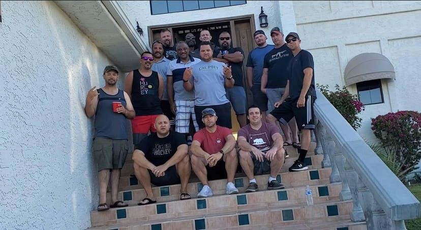 Whole crew on the front steps of the house — full lineup, sun going down