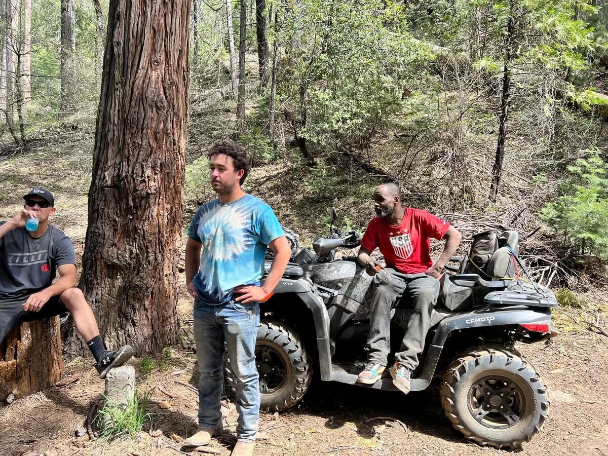 Standing around the CFMOTO under the cedars — Killin shirt, tie-dye, USA red