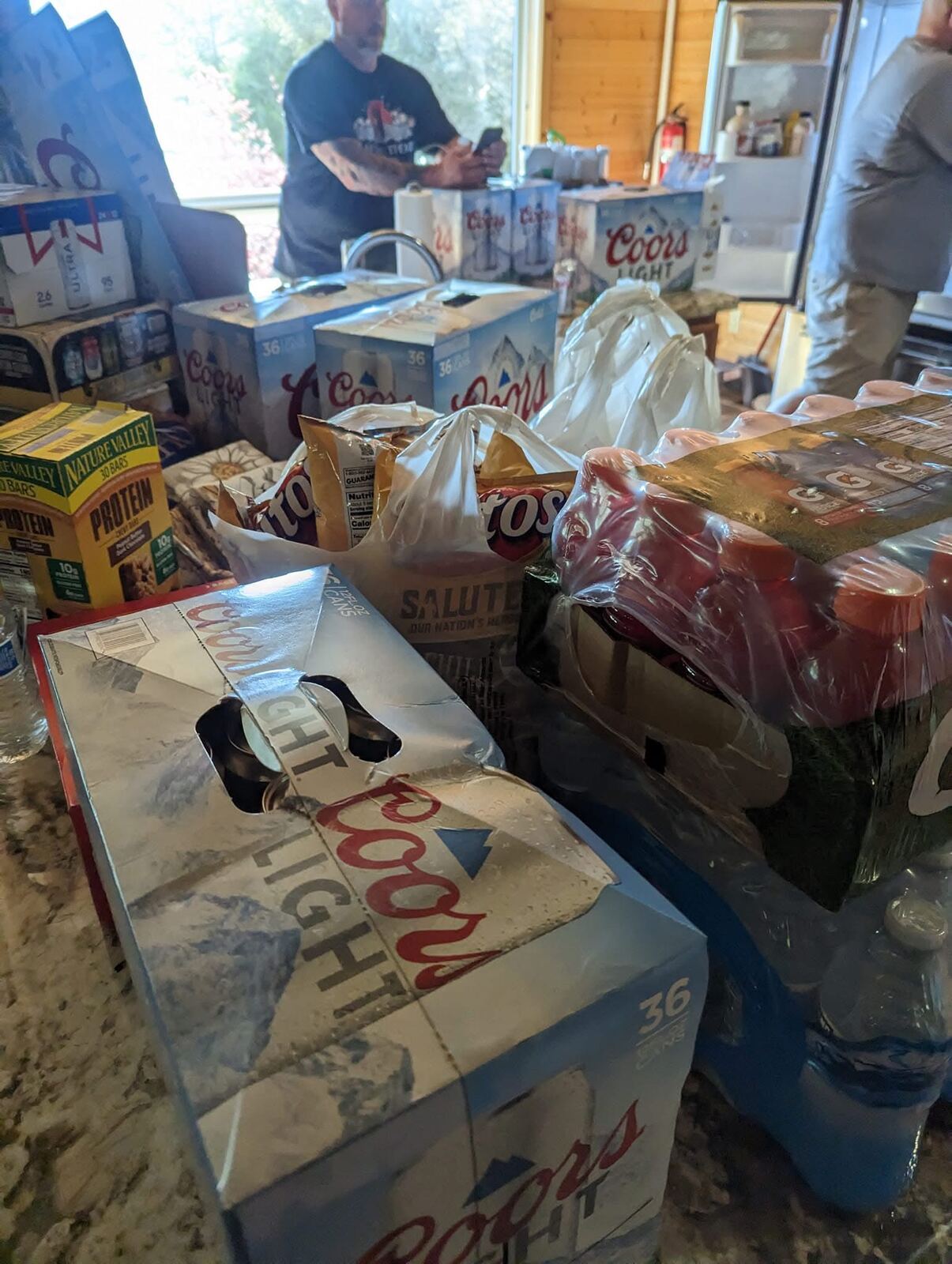 Cabin counter loaded out — Coors Light cases, chips, and a full beer fridge
