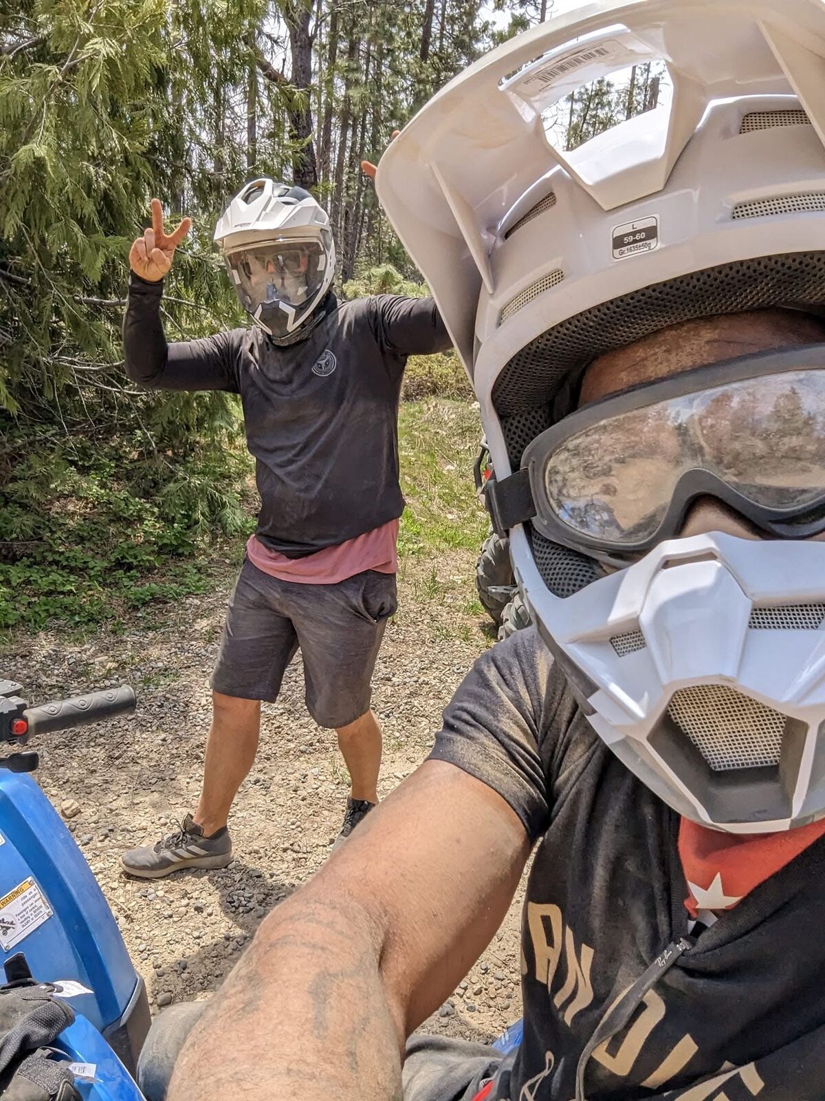 Dirt bike day — helmets on, gloves off, peace sign in the trees