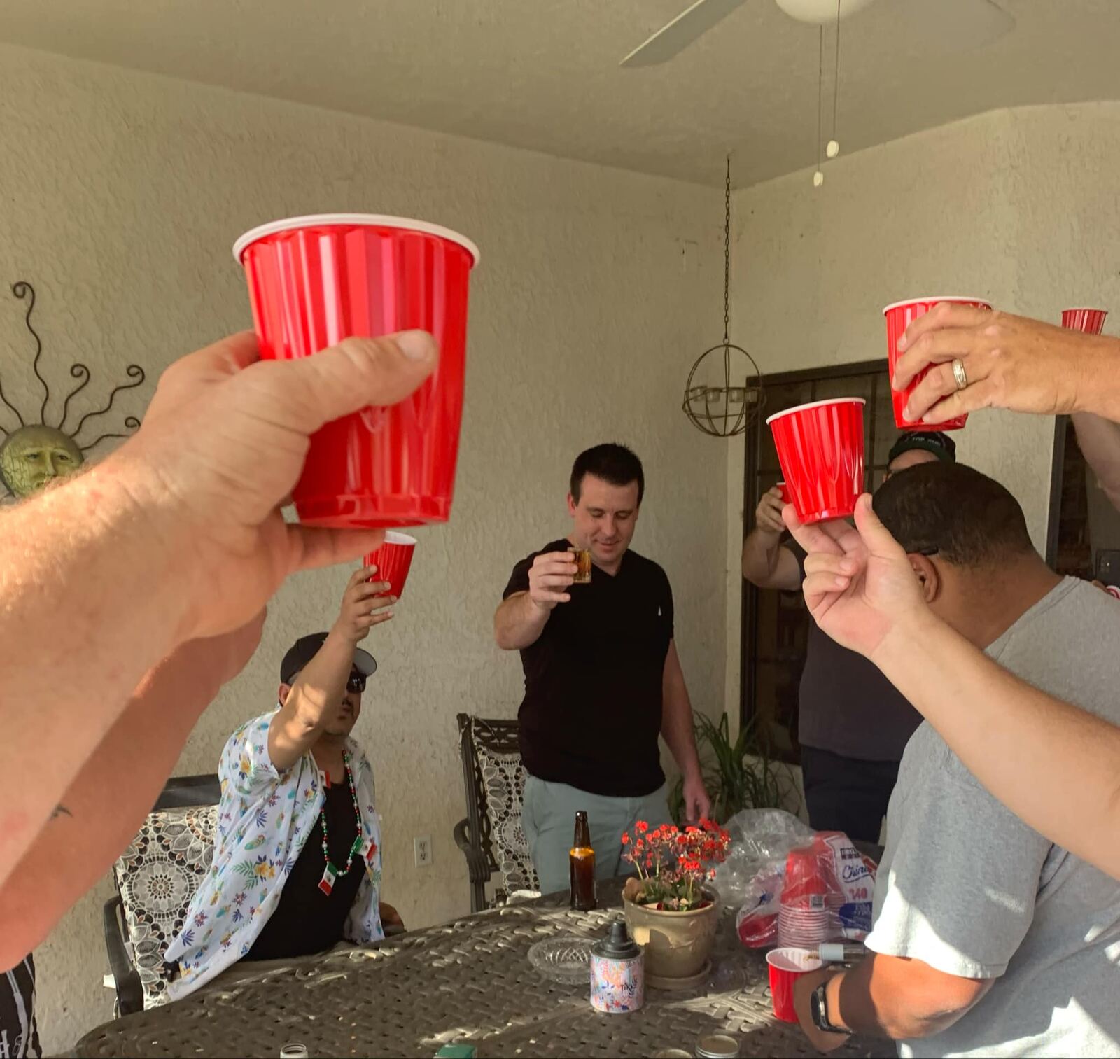 Red Solo cups raised over the table — tequila shot in the middle