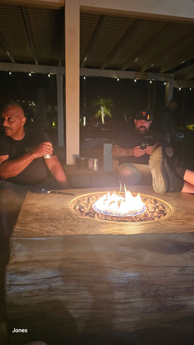 Firepit hangout under string lights — beers, phones, brotherhood
