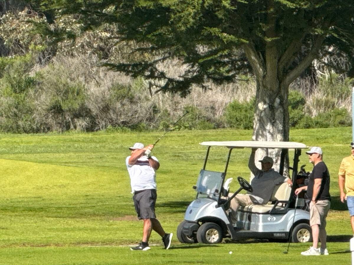Mid-swing on the fairway with the cart waiting