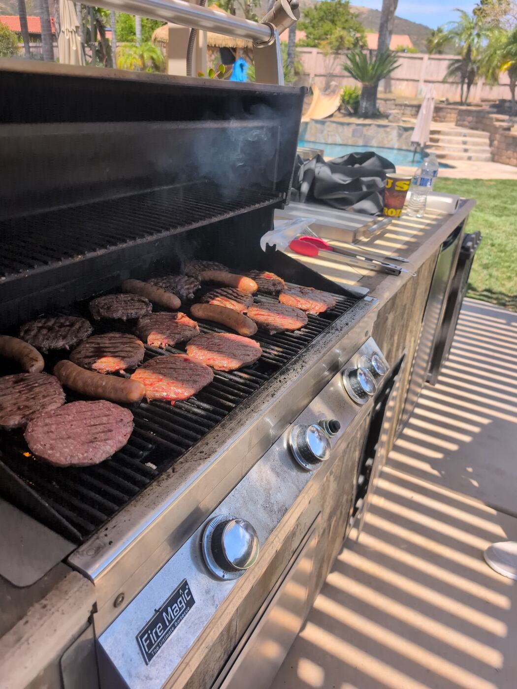 Fire Magic loaded — burgers, sausages and steaks over the flame