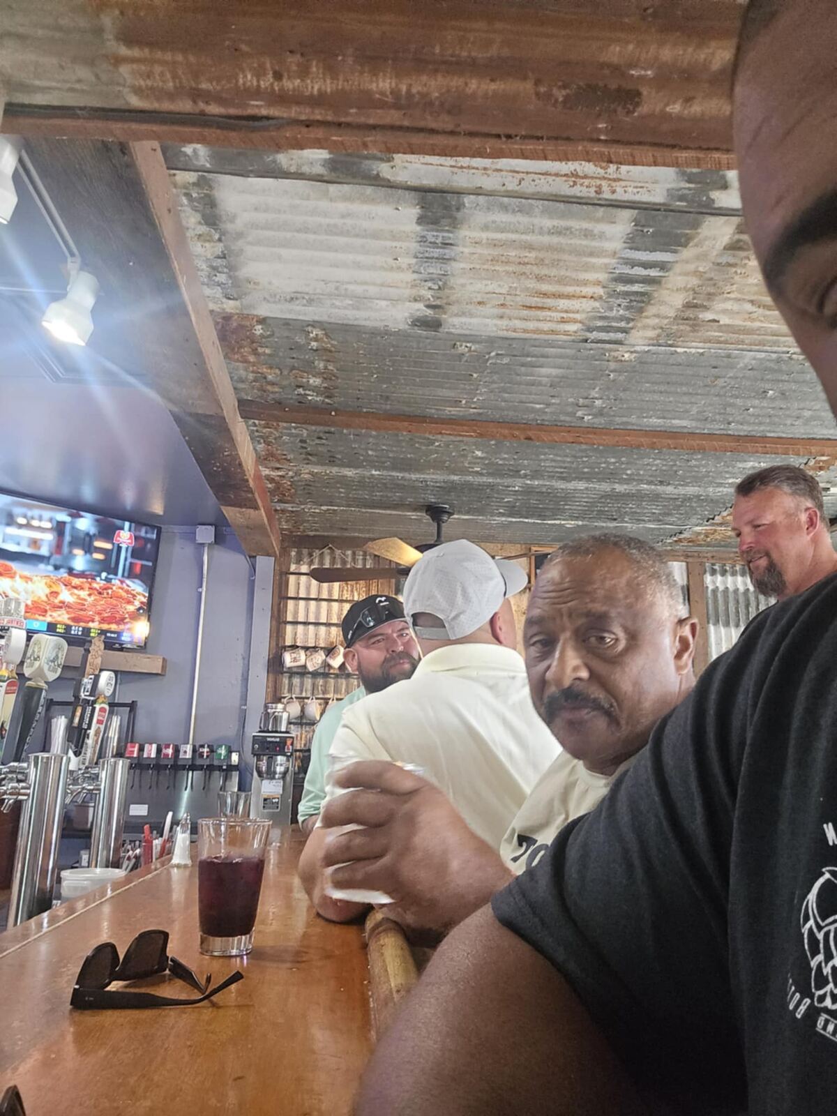 Tin-roof dive bar, pizza on the screen, brothers at the rail