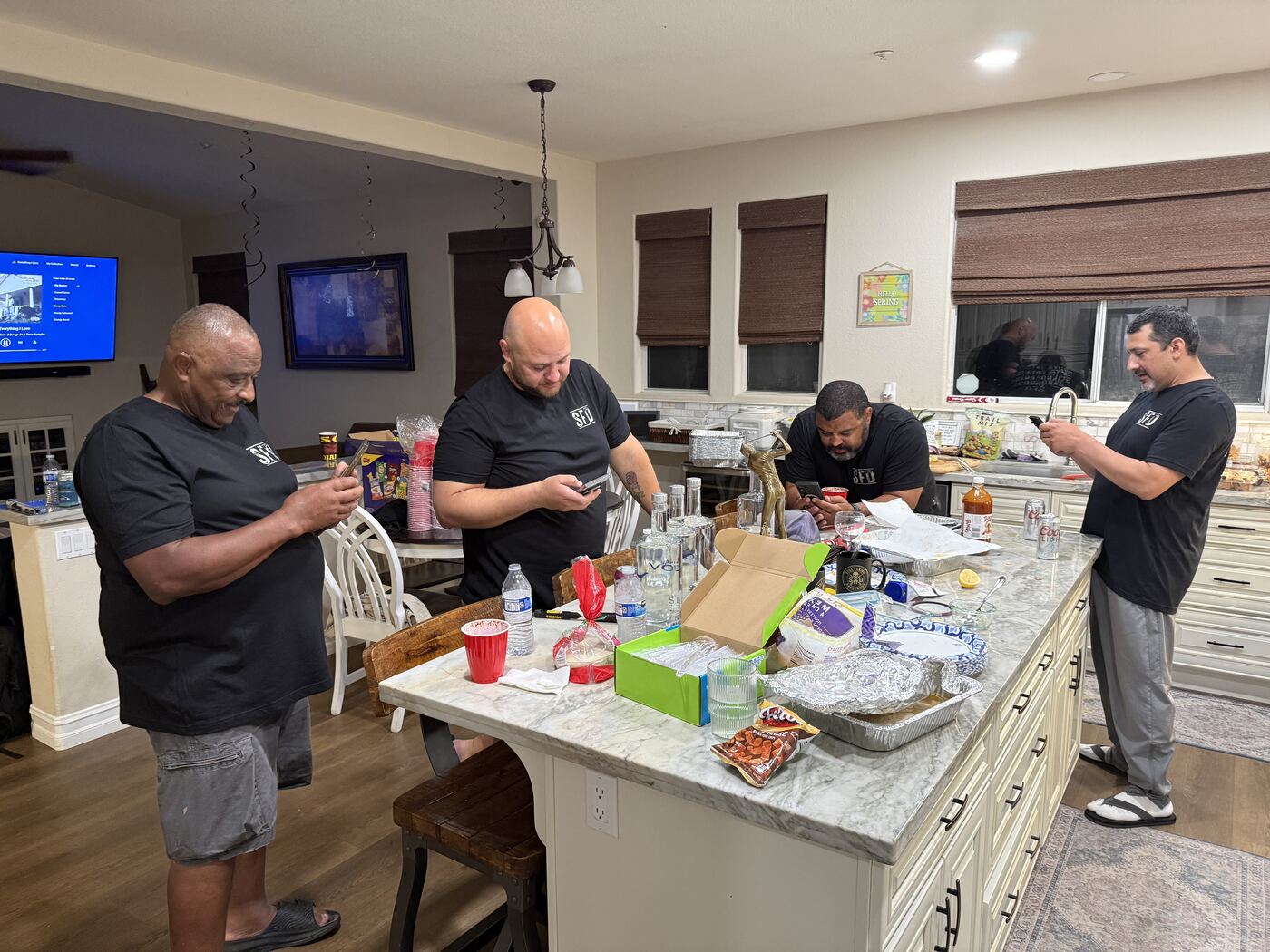 Kitchen island huddle — phones out, snacks open, plans being made
