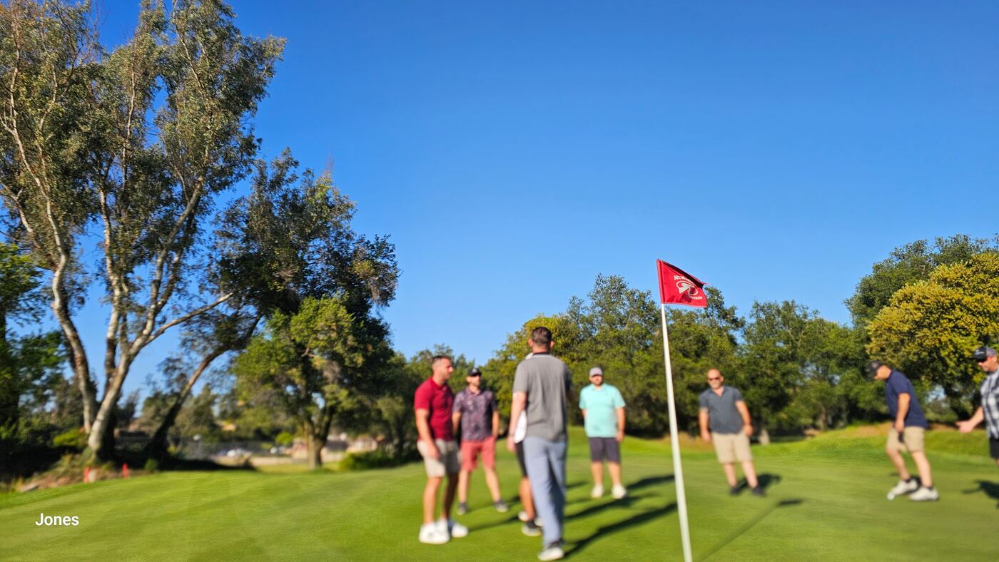 Wide shot of the Jones green — flag in the breeze, brothers gathering