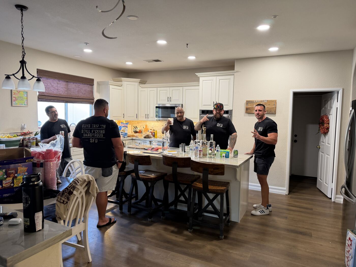 Morning crew in the kitchen — Guys Trip '26 'Still F’cking Dangerous' tee front and center