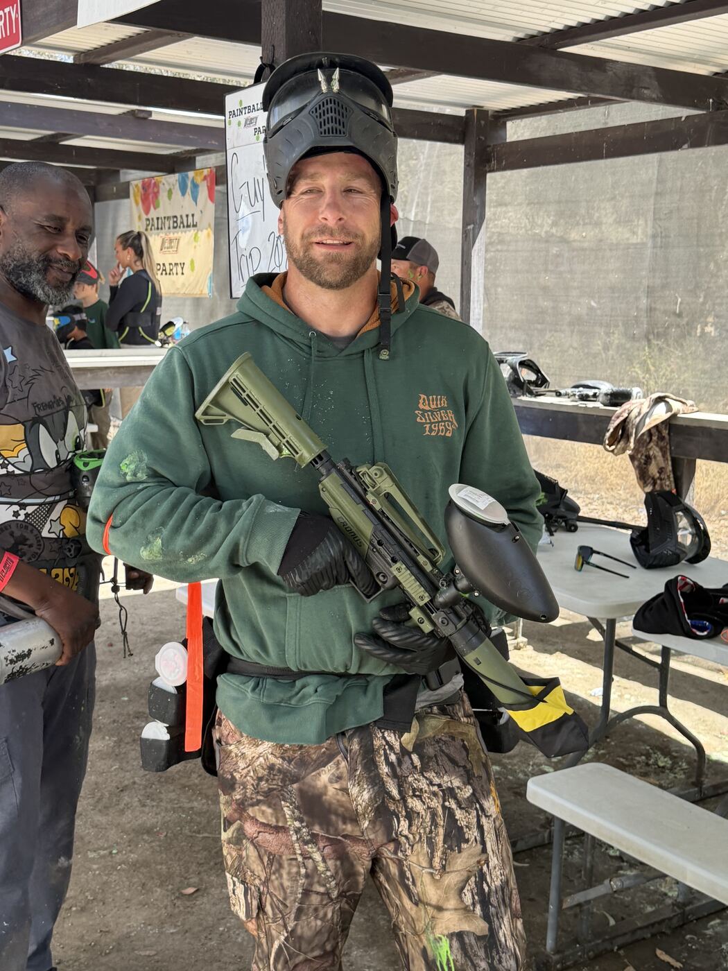Suited up for paintball — camo pants, marker loaded, ready to roll