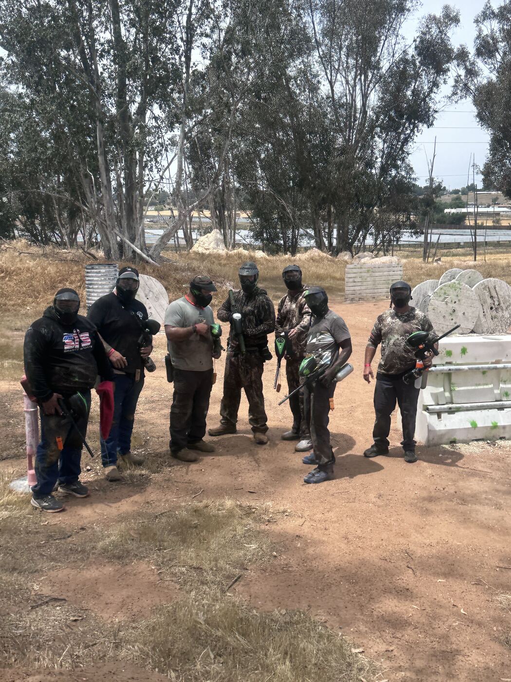 Paintball squad after a hard run — camo, masks and gear caked in dirt