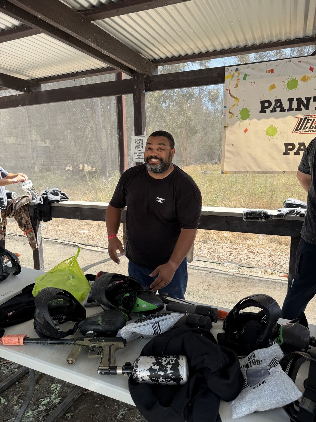 Paintball table loaded out — markers, masks, hoppers and tanks