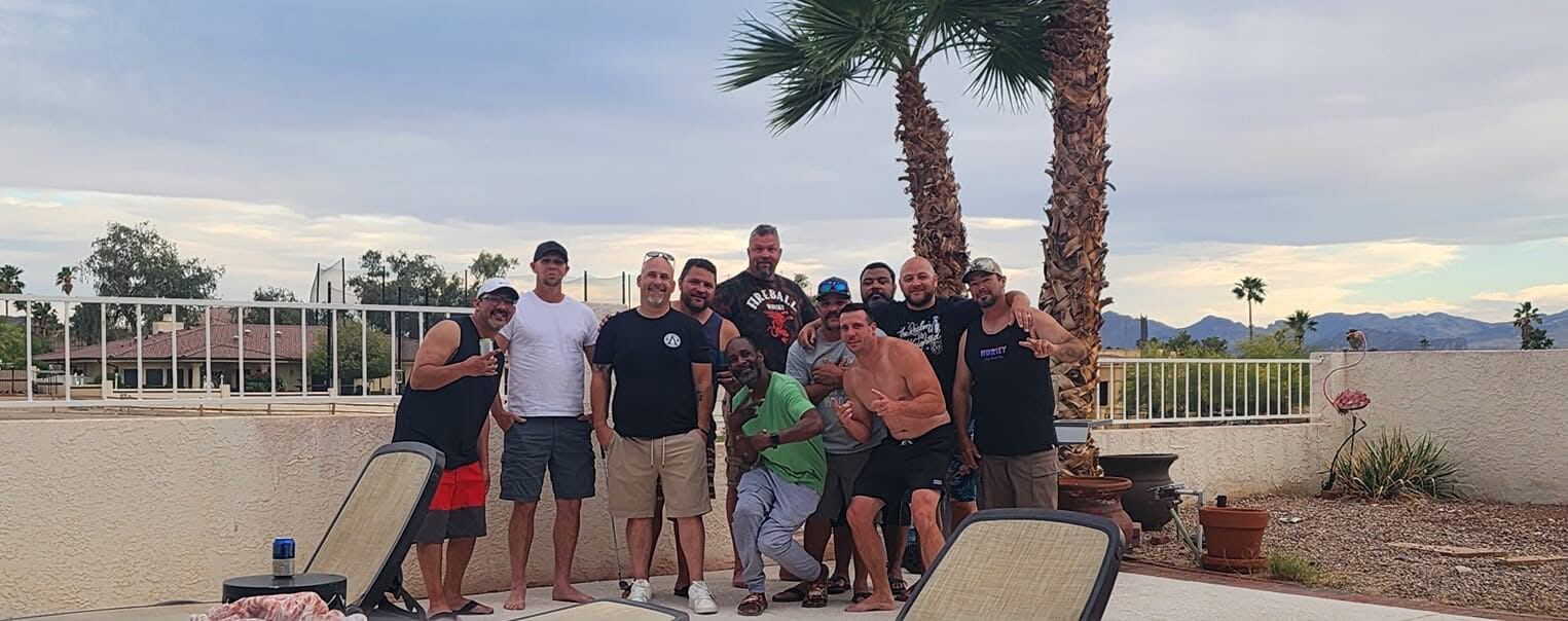 Backyard group shot under the palms — Havasu evening, mountains in the distance