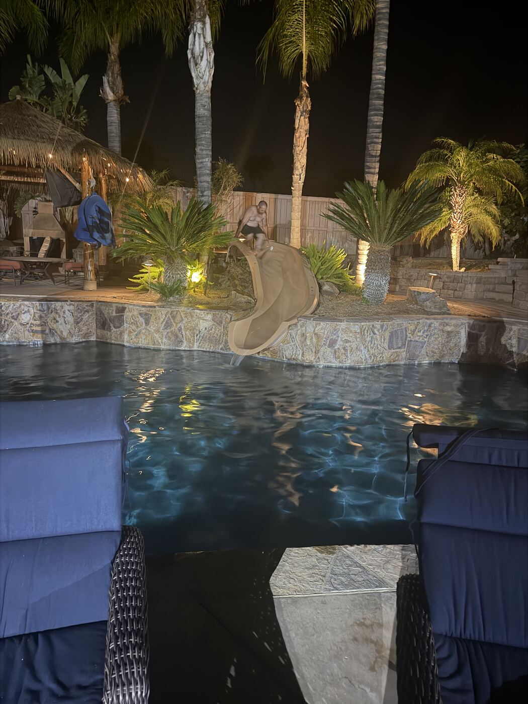 Hitting the pool slide at night — palms up, lights low, full send