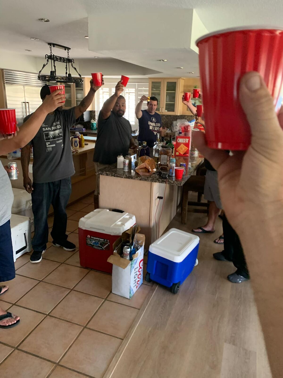 Solo cups raised over the kitchen island — coolers stacked, party starting