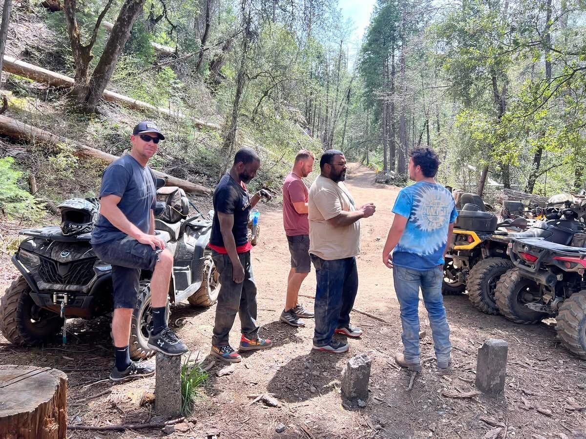 Trail break in the pines — quads parked, brothers talking it out