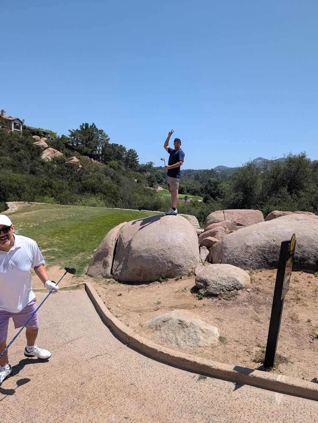 Tee box on the rocks — peace sign up over the canyon, club in hand