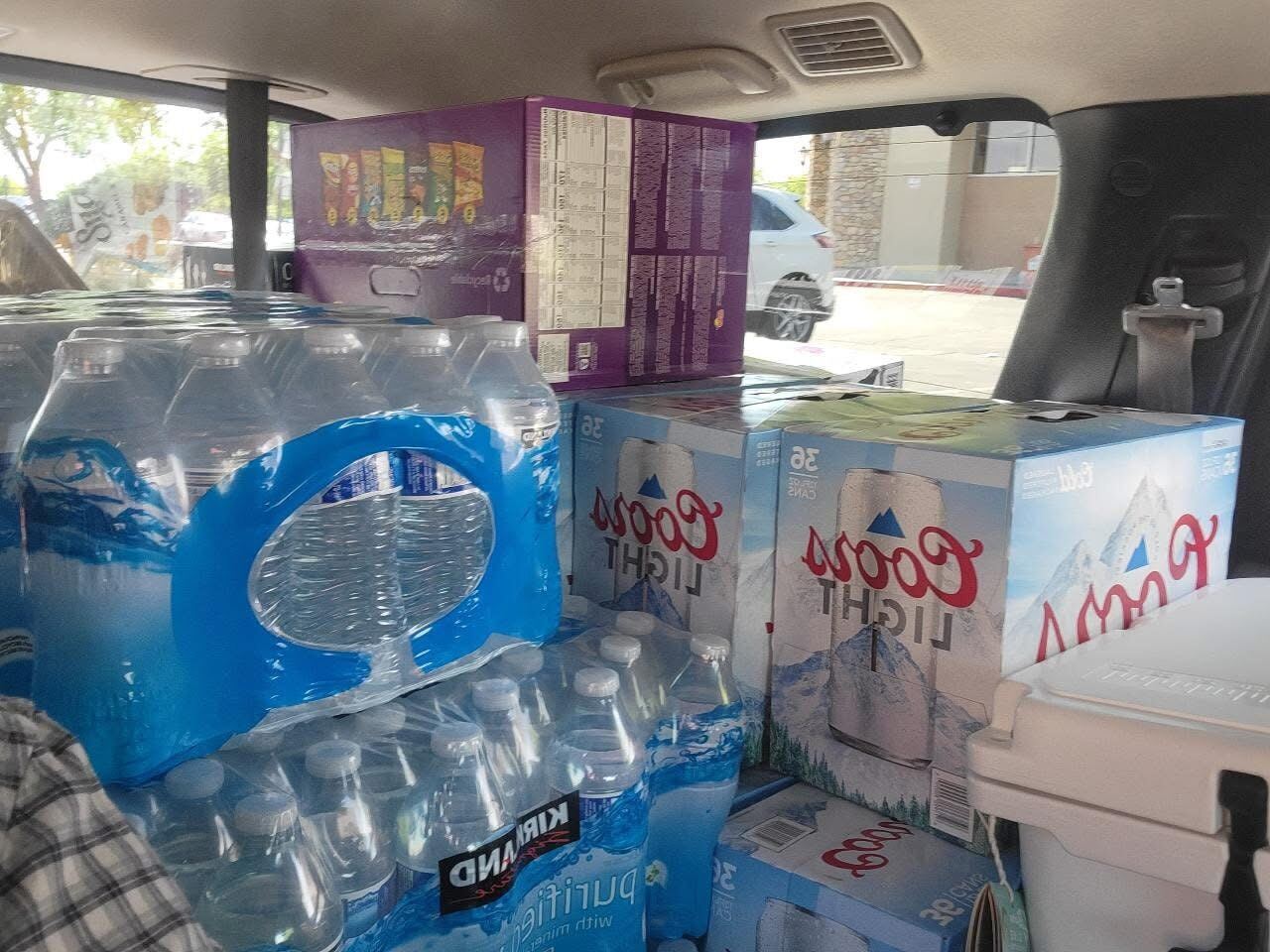 SUV loaded floor to ceiling — Coors Light, Kirkland water, snacks for the week