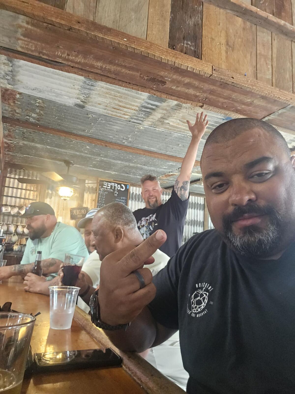 Dive-bar selfie — hand up in the back, story in motion
