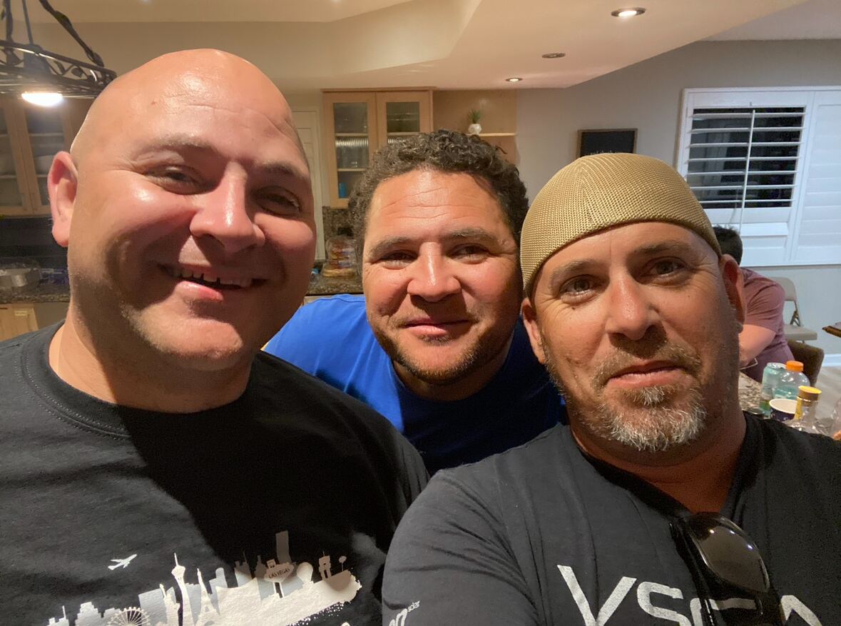 Late-night kitchen selfie — three brothers, big grins, full house behind